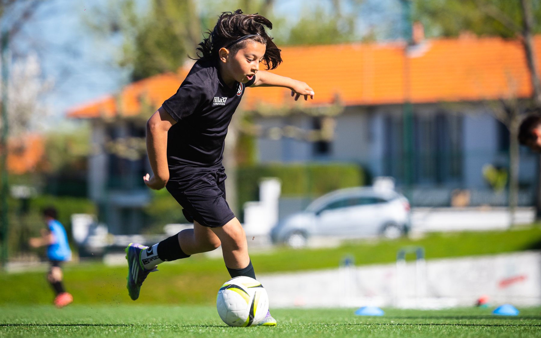 Jeune joueuse en noir qui conduit le ballon à l'entraînement