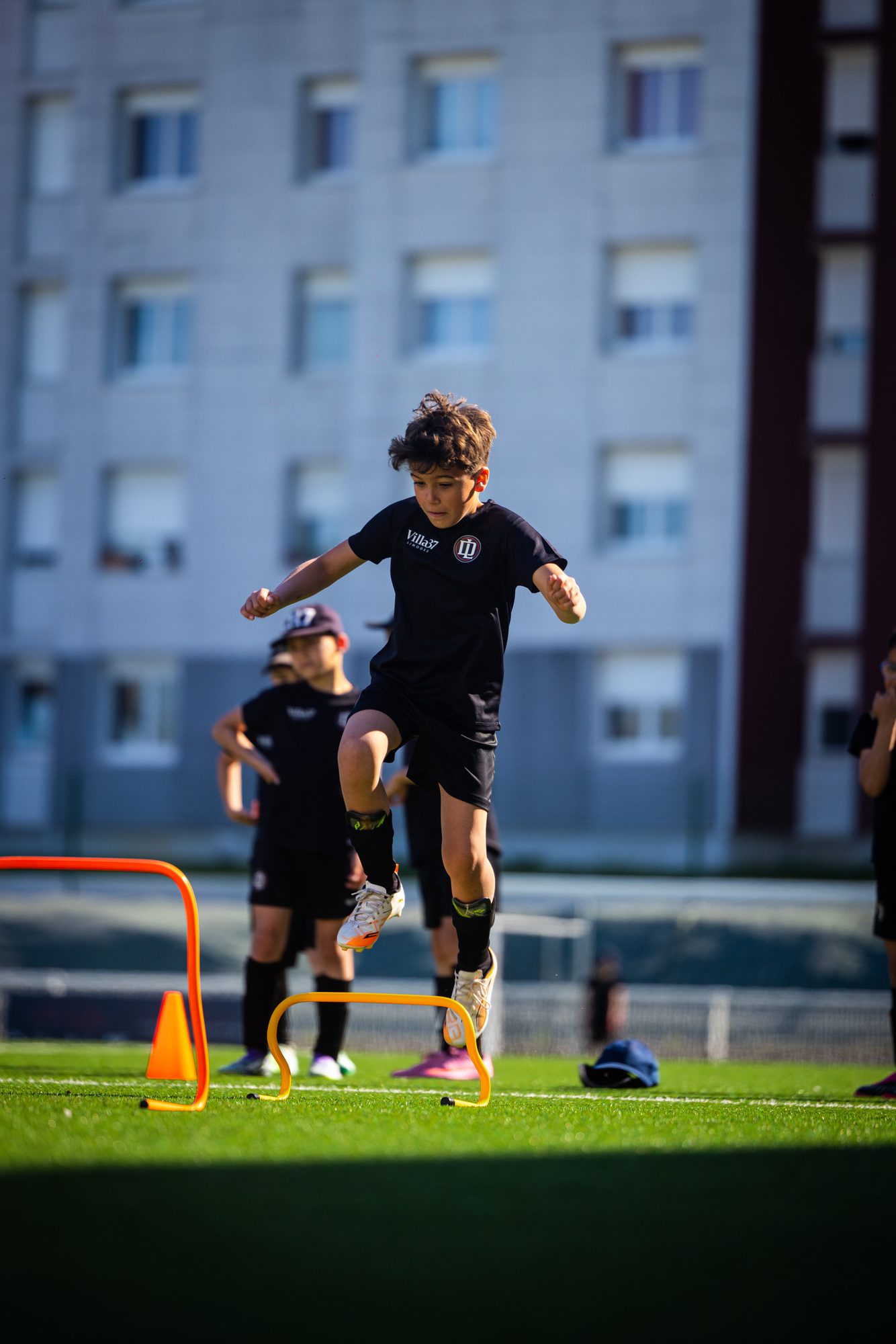 Jeune joueur qui franchit une haie à l'entraînement